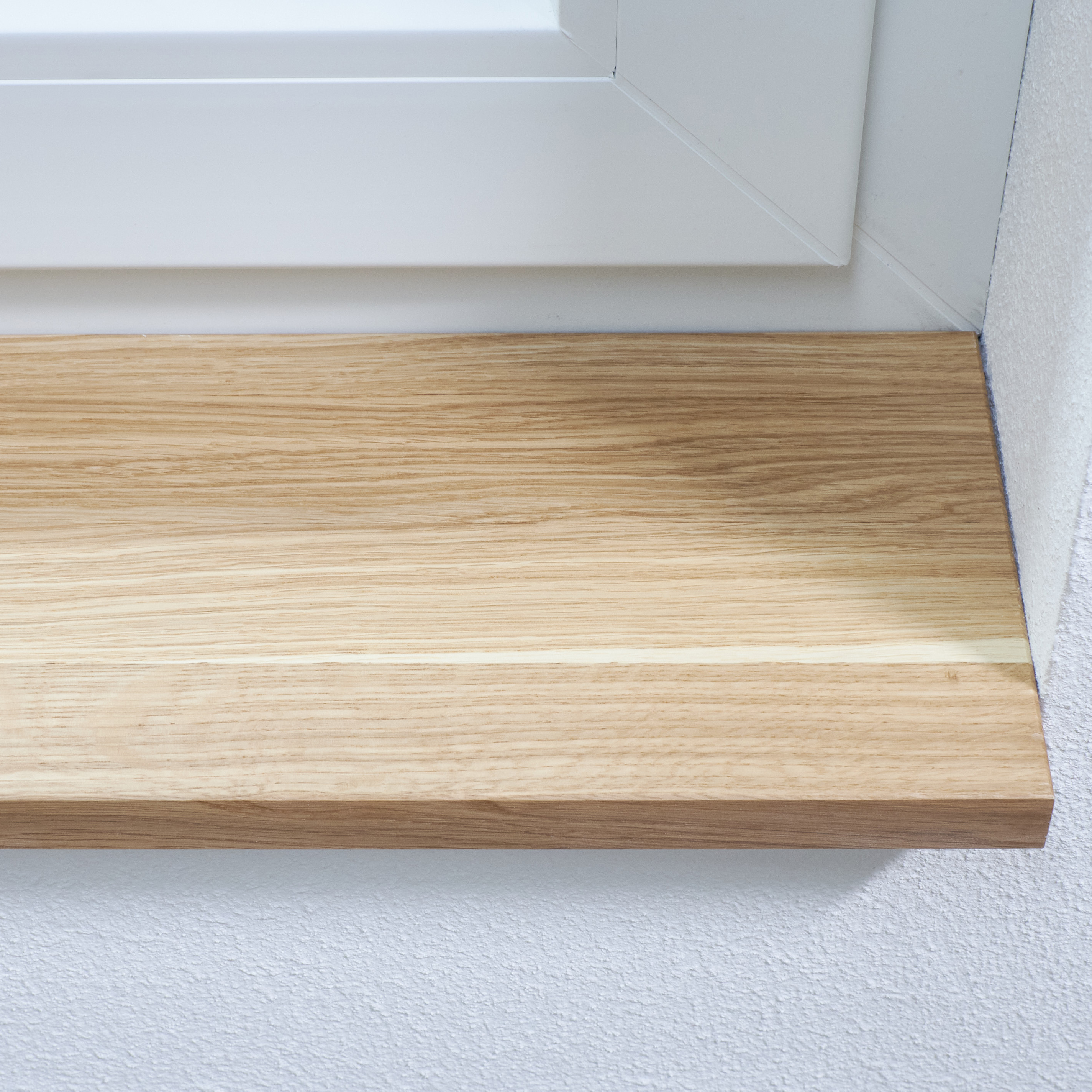 Vensterbank van massief eikenhout naturel, ingebouwd onder wit raamkozijn, close-up van de nerf