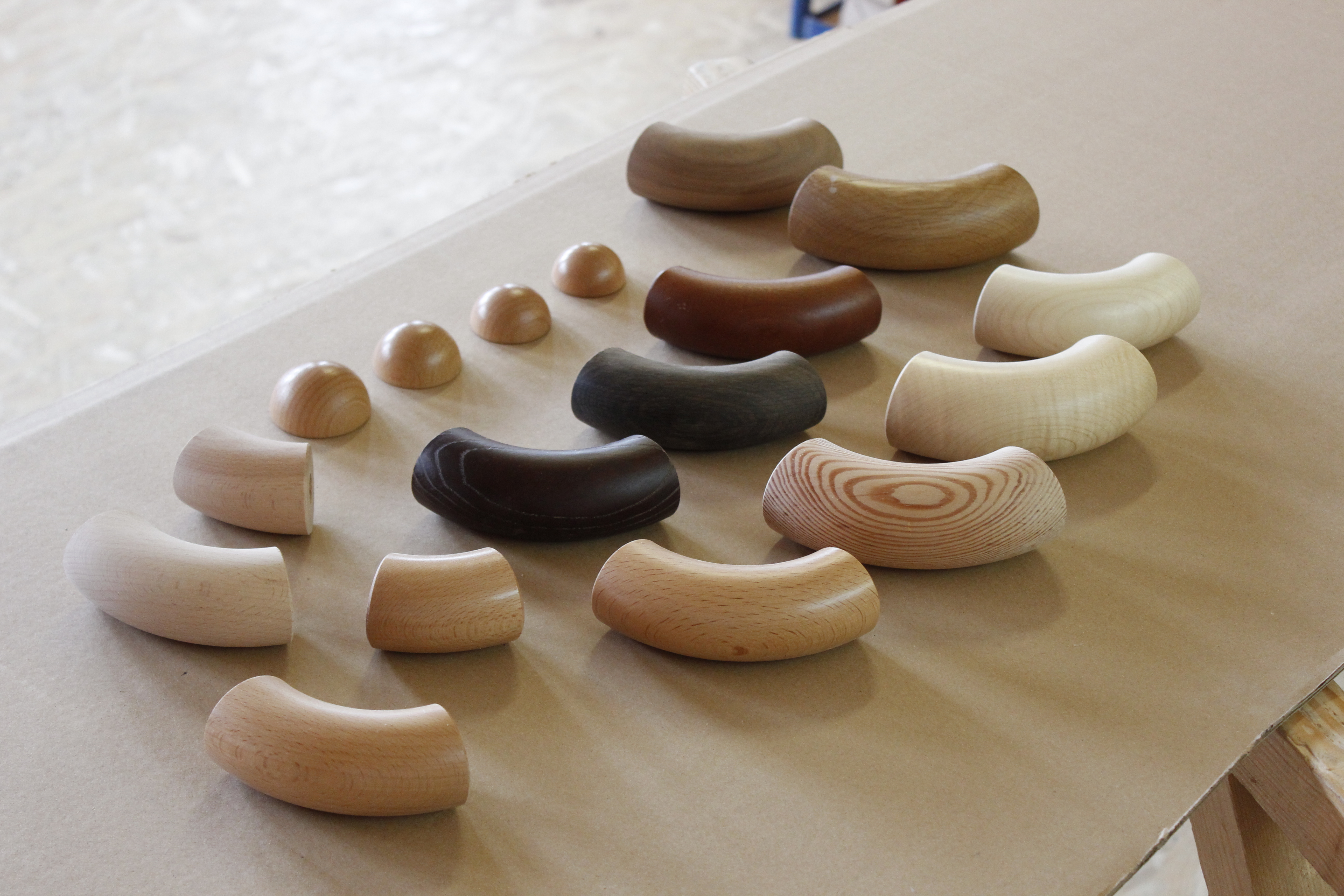 Leuningaccessoires van hout: leuningbochten en halfronde eindkappen in verschillende houtsoorten op papier in de werkplaats