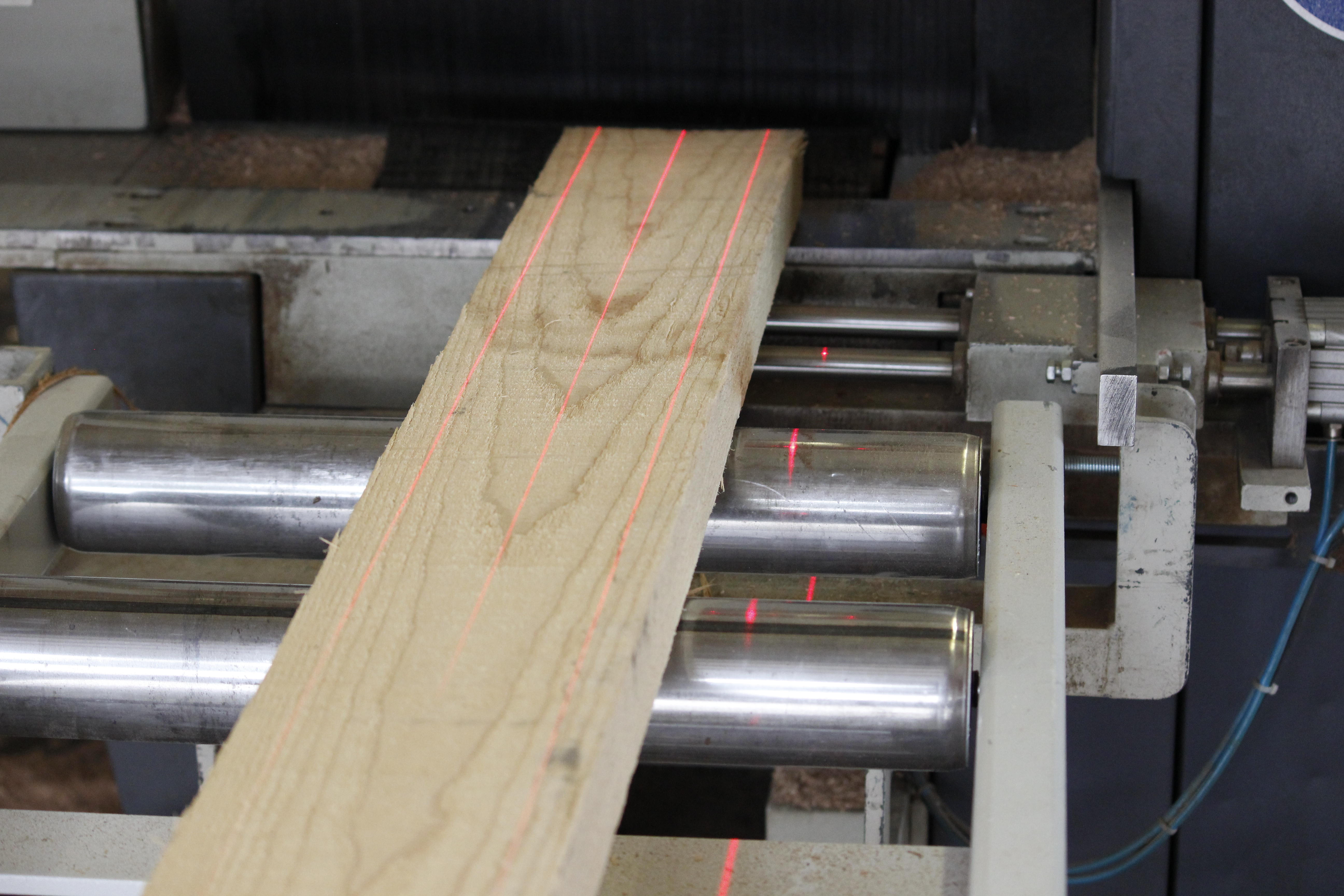 Houten plank op machinerollen met rode laserlijnen bij het nauwkeurig op maat zagen in de vensterbankproductie