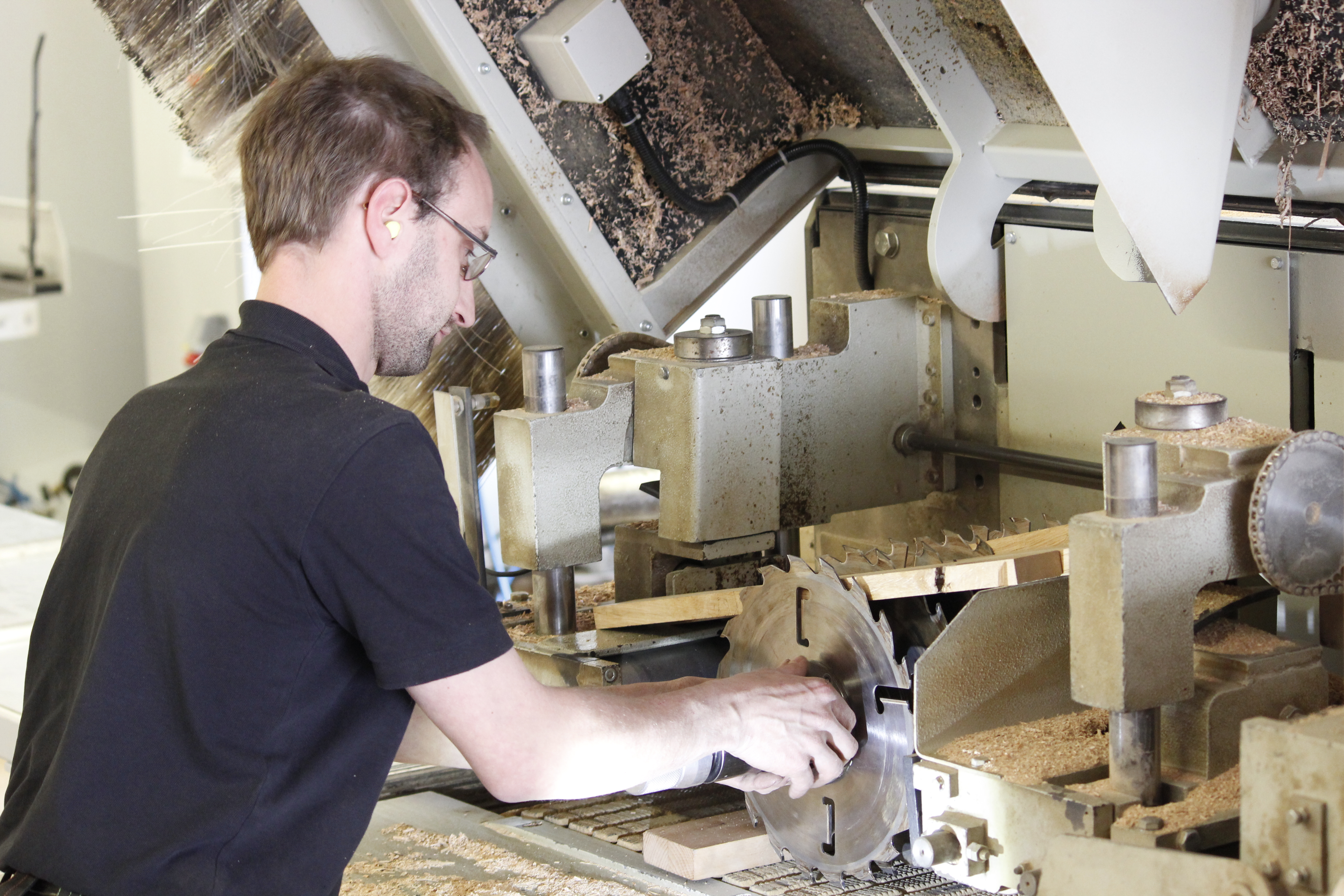 Houtbewerker aan een schaafmachine in de werkplaats bij het bewerken van massief hout, spaanders op de machine