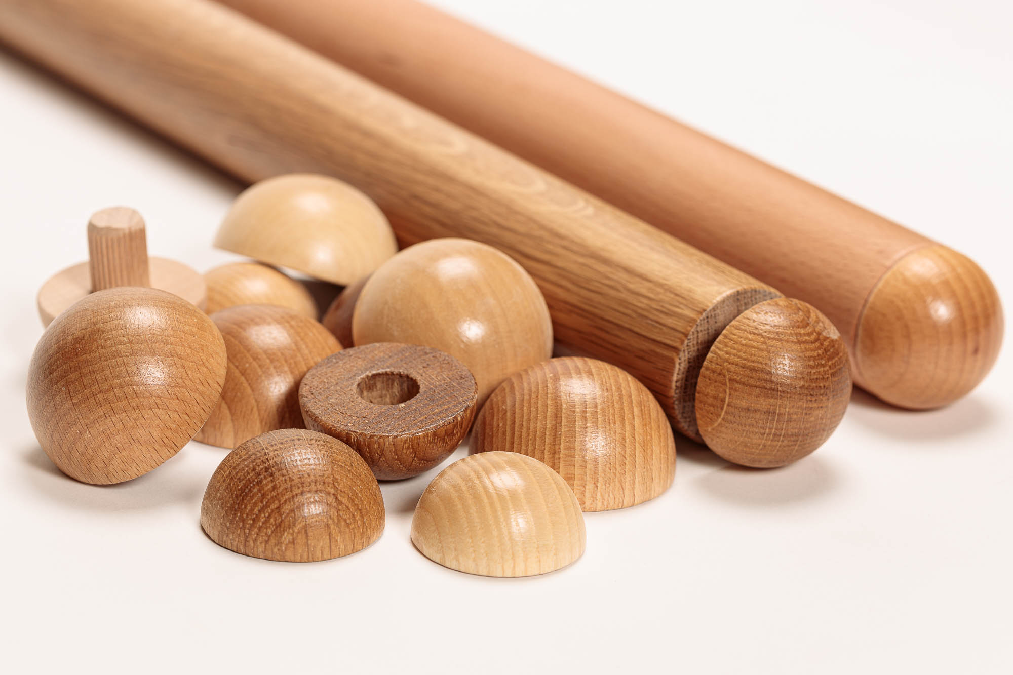 Houten eindkappen voor ronde leuningen in diverse houtsoorten, halve bollen met plug en boring naast twee ronde leuningen