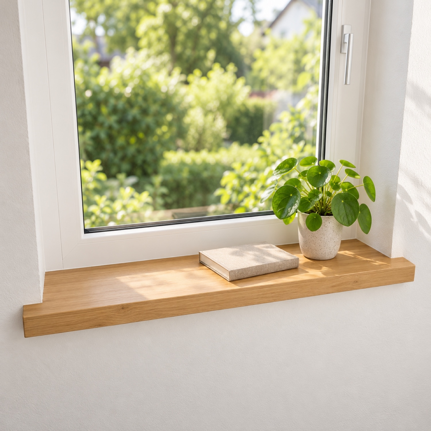 Renovatievensterbank van eikenhout, naturel, massief hout, voor wit raam met tuinzicht, pilea in witte pot en boek